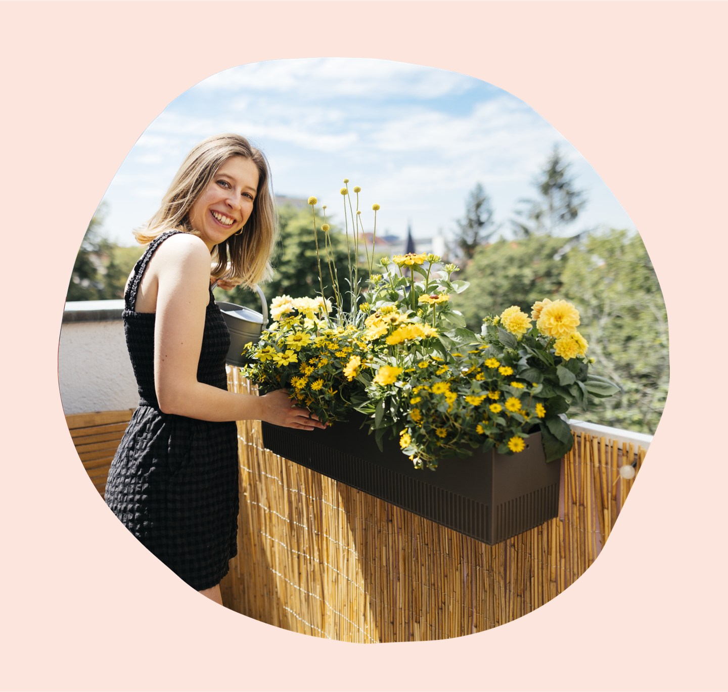 Lächelnde Frau in Sommerkleid neben blumengefüllter Balkonbox