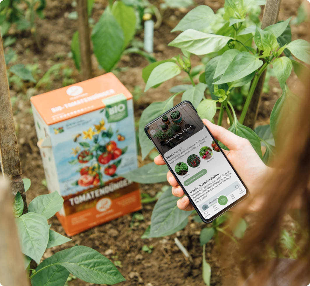 Frau nutzt Plantura App im Garten