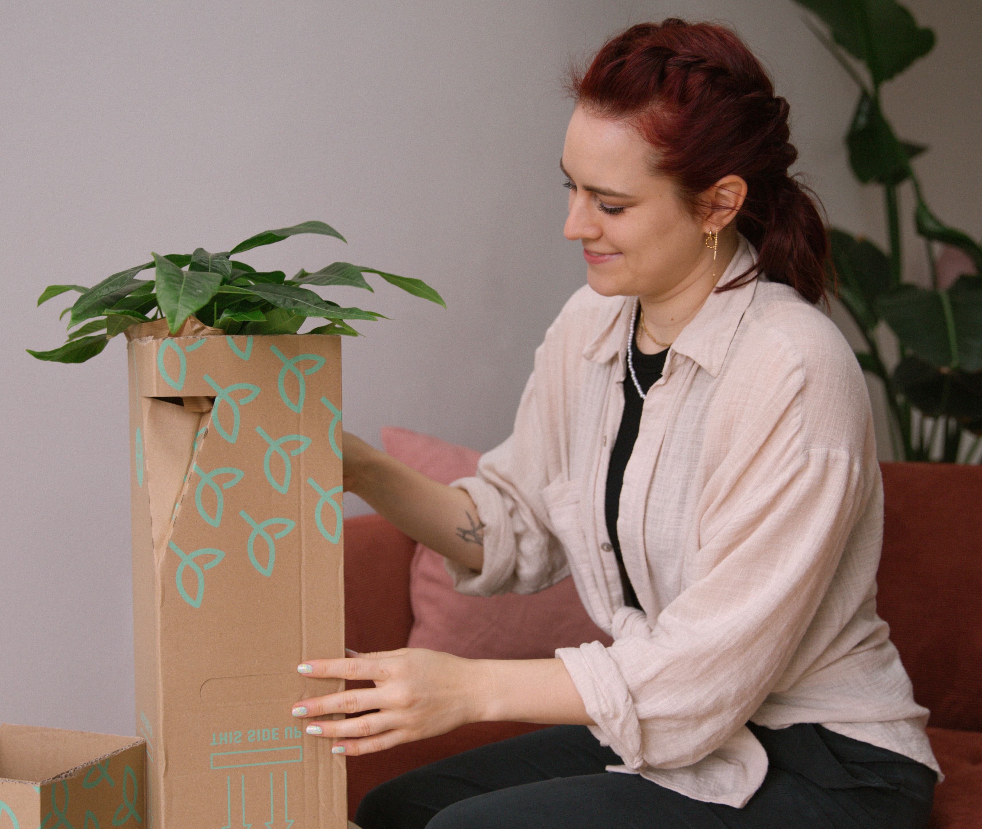 Frau packt Zimmerpflanzen-Paket aus